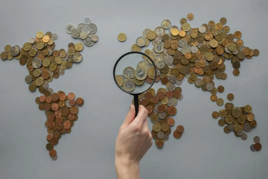 A magnifying glass held over a world map made of coins