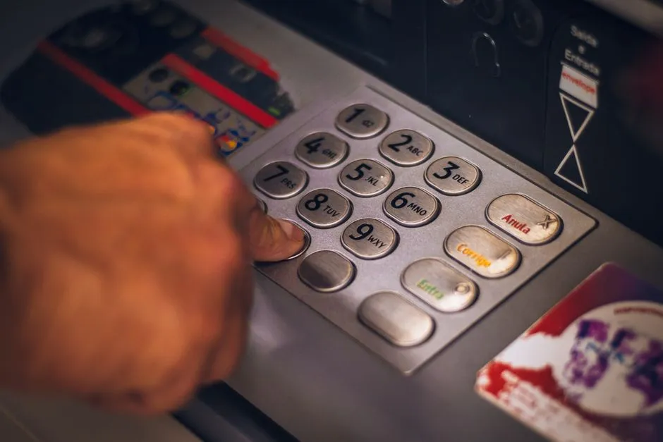 A person entering a PIN at an ATM keypad